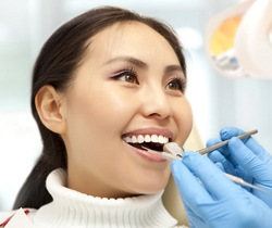 Dentist examining woman's smile after dental crown restoration