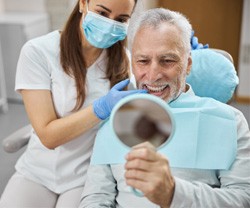 dentist smiling while looking in dental mirror 