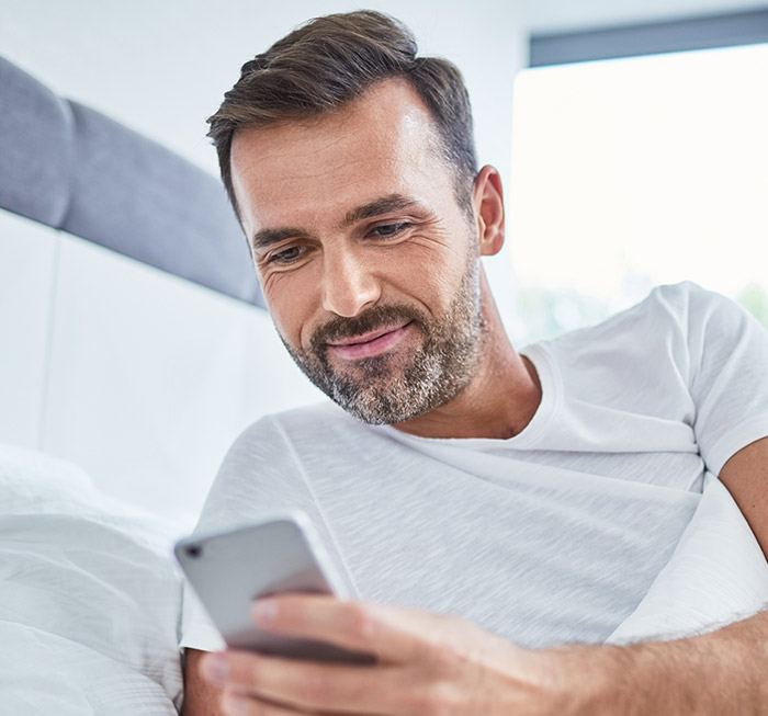Man in bed checking cell phone