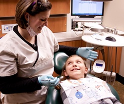 Team member treating young child in dental exam rooom