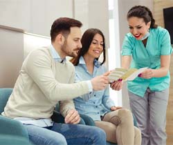 dental team member showing a pamphlet to two patients