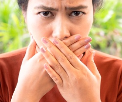 Woman covering mouth to hide signs of oral myofunctional disorders