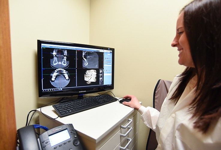 Dental team member looking at digital x-rays on computer screen