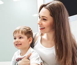 Woman holding child in her lap during fluoride treatment