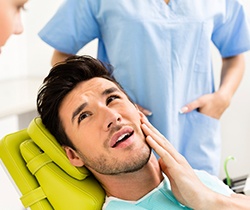 Man in dental chair holding jaw before T M J therapy