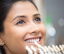 Woman's smile compared with porcelain veneer color chart