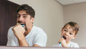 father and son brushing teeth