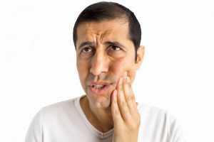 man holding left jaw in pain