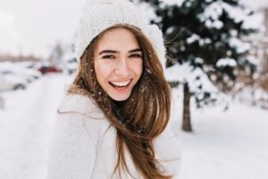 Woman standing outside in the snow wearing a winter hat and smiling
